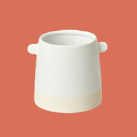 White ceramic pot with handles on a terracotta background from House of Agave.