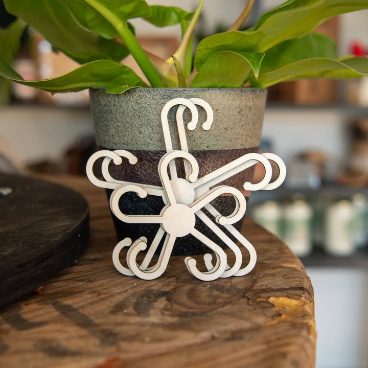 Decorative white metal plant hanger on a wooden surface with a blurred background